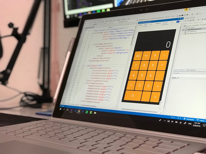 A close-up view of a laptop computer displaying a code editor on the left side and a calculator interface with orange buttons on the right side. The code editor contains lines of HTML and CSS syntax,